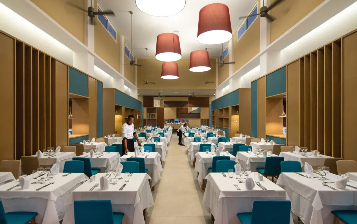 Large dining room with white tablecloths and teal chairs at Hotel Riu Palace Tropical Bay.