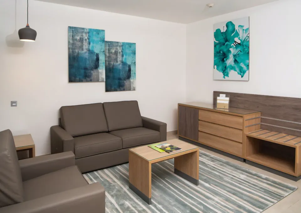 Ocean View suite lounge with sofa, armchair, and dresser at Hotel Riu Palace Tropical Bay.
