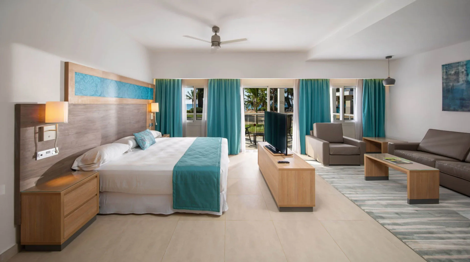 Suite room with king bed and seating area at Hotel Riu Palace Tropical Bay.
