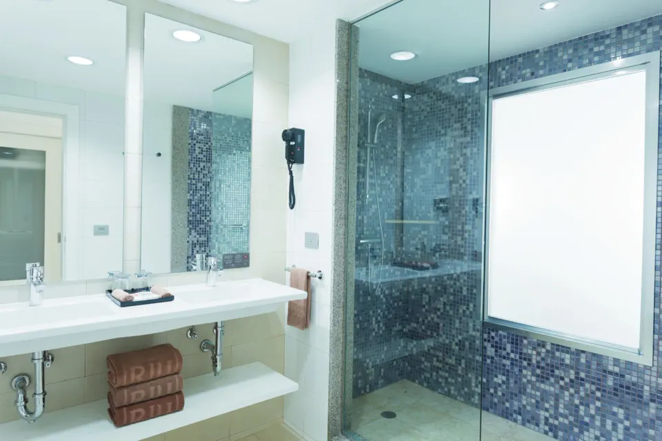 Bright bathroom with large frosted window and glass shower at Hotel Riu Playacar