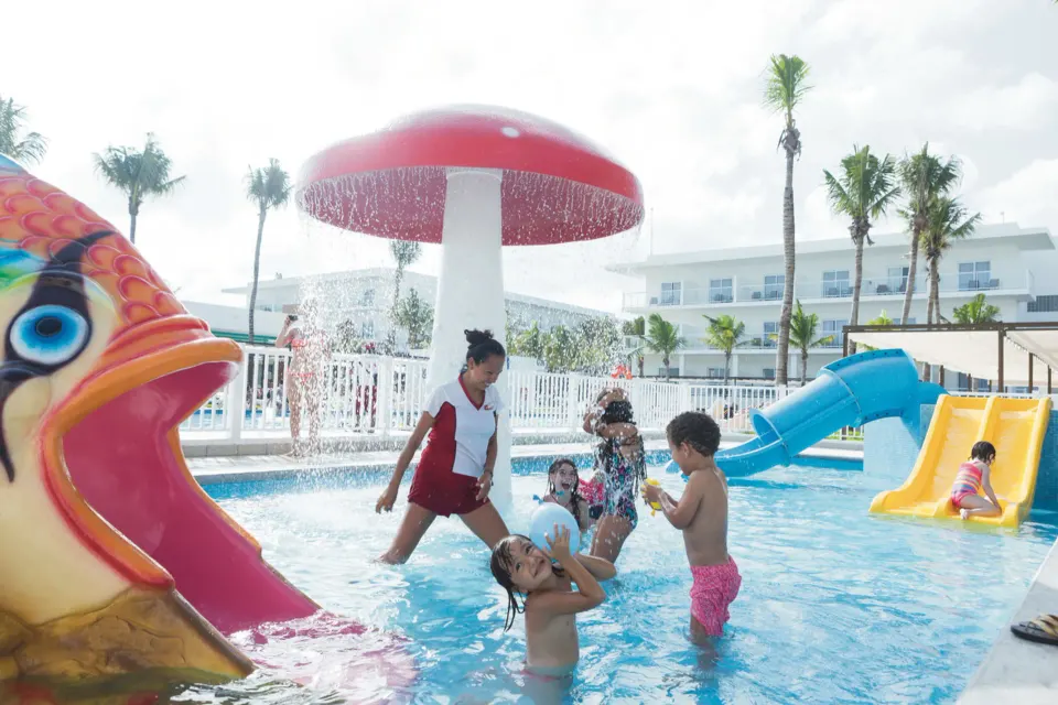Children playing under a mushroom fountain in the kids pool at Hotel Riu Playacar.