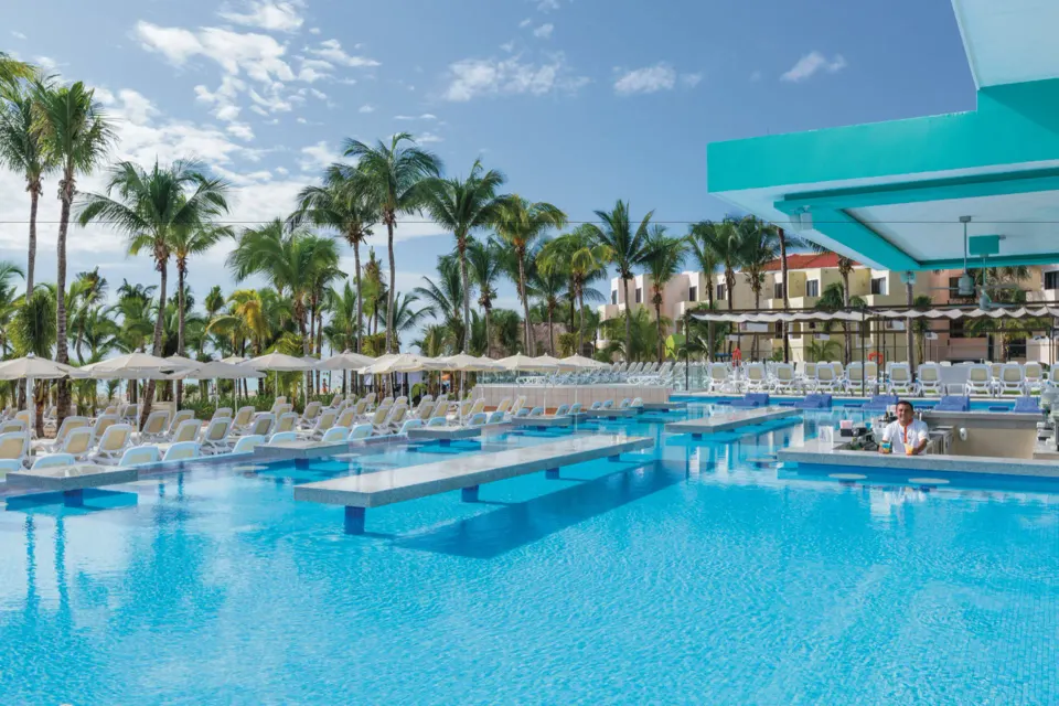 Main resort pool with swim-up bar and rows of sunbeds at Hotel Riu Playacar