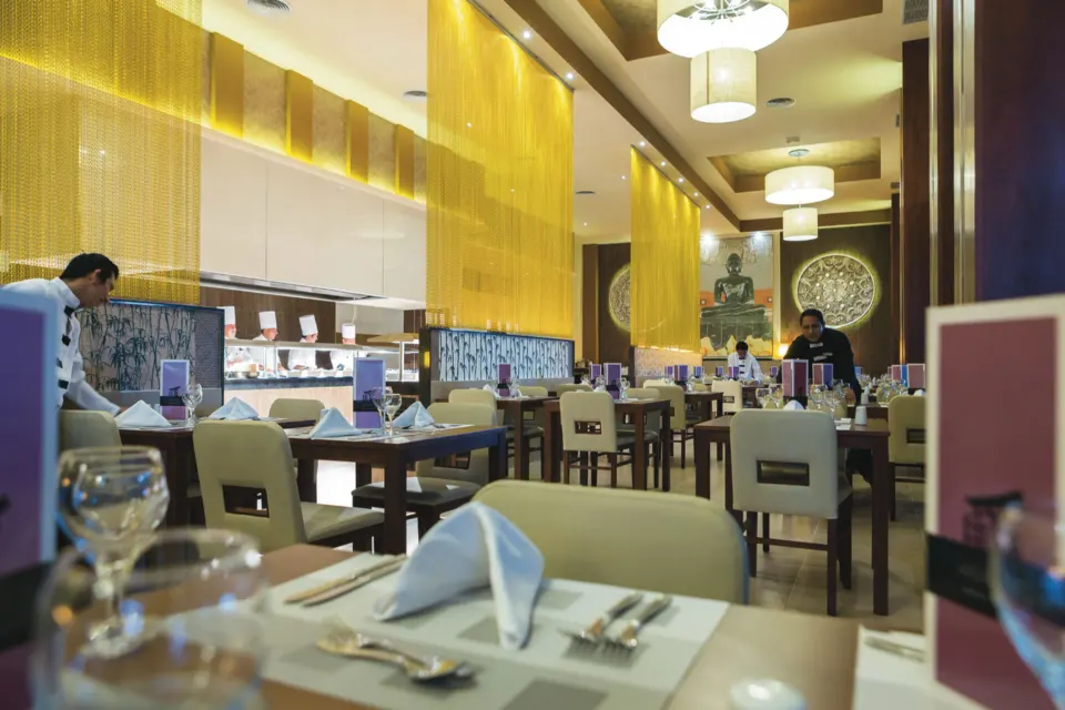 Asian-themed restaurant interior with decorative screens and Buddha artwork at Hotel Riu Playacar.