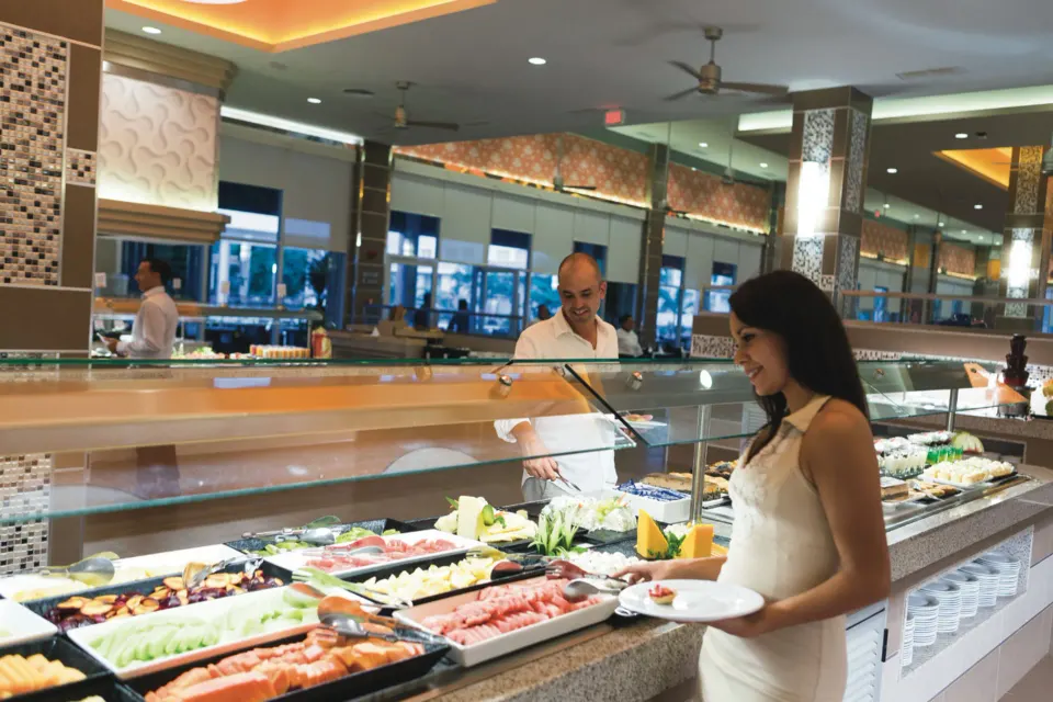 Guest selecting fresh fruit and cold items at the buffet at Hotel Riu Playacar