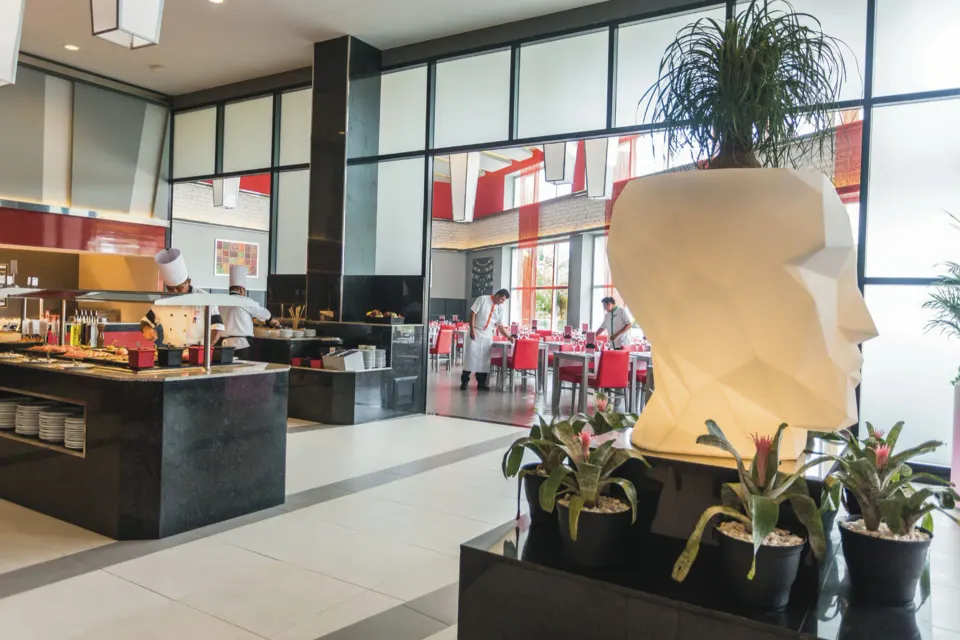 Buffet area and sculptural planter with seating beyond at Hotel Riu Playacar.