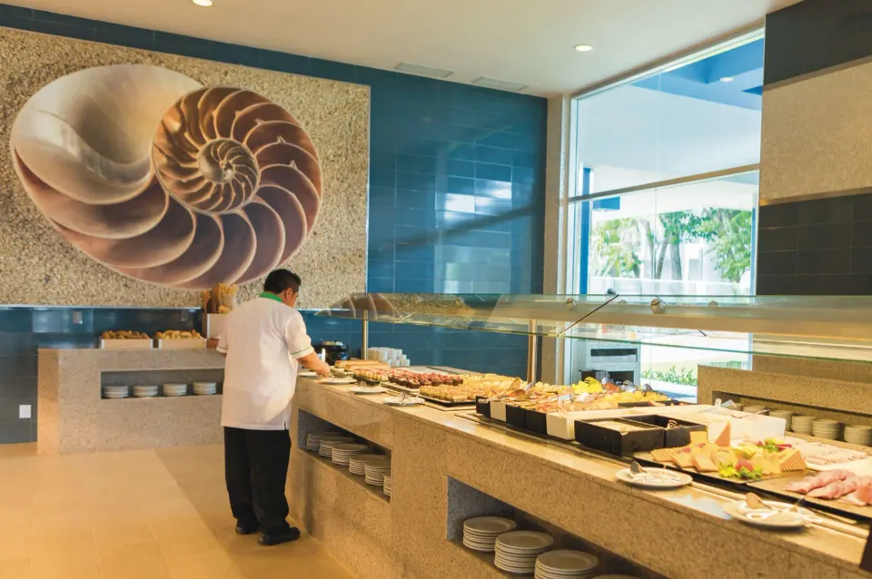 Buffet counter with seafood and salads and a shell mural at Hotel Riu Playacar