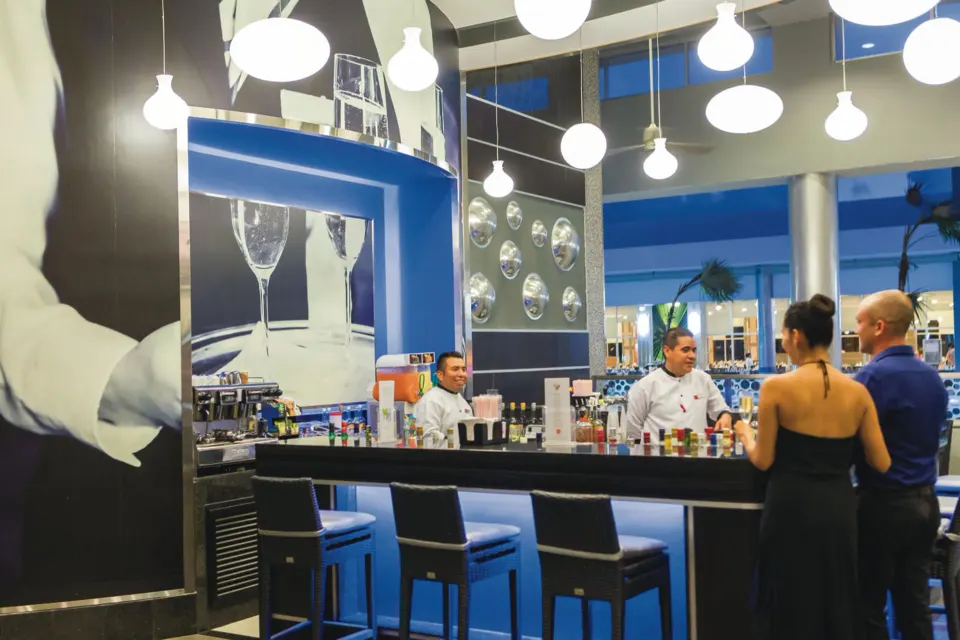 Interior bar counter with bartenders and guests at Hotel Riu Playacar