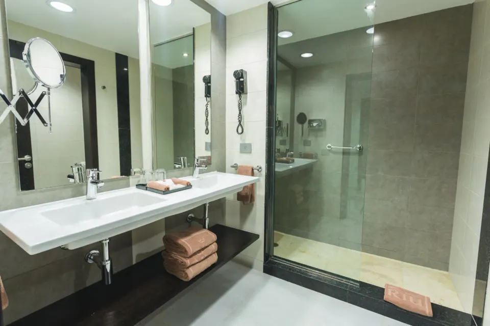 Bathroom with double sink and glass shower in a Junior Suite at Hotel Riu Playacar