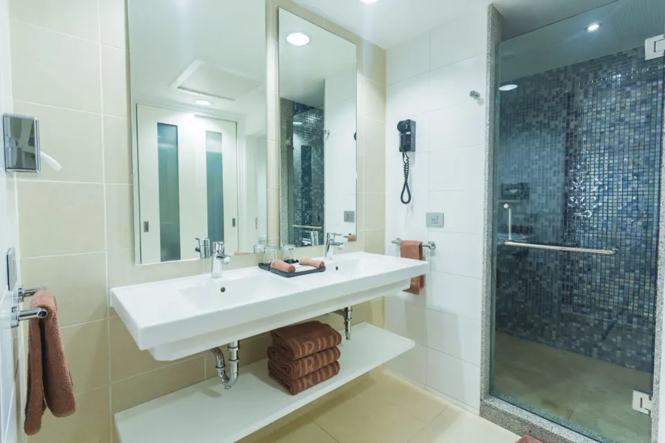 Bathroom vanity with double sinks and glass-door shower in a guest room at Hotel Riu Playacar