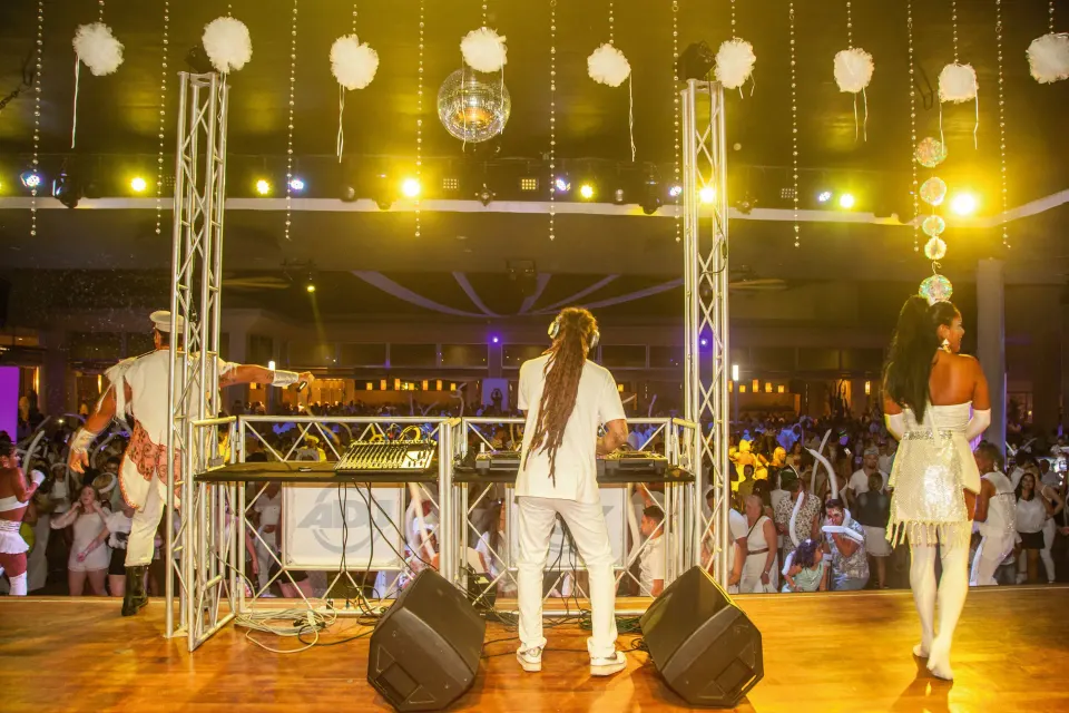 DJ and performers onstage facing a cheering crowd under disco lights at Hotel Riu Playacar