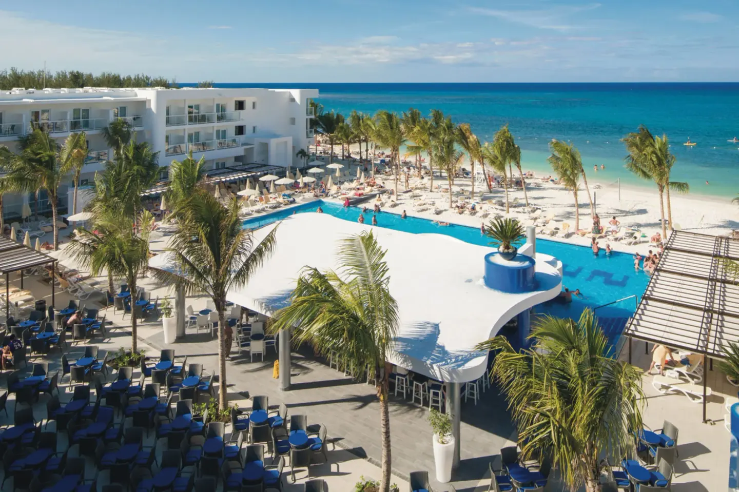 Elevated view of pool, terrace seating, beach, and sea at Hotel Riu Reggae.