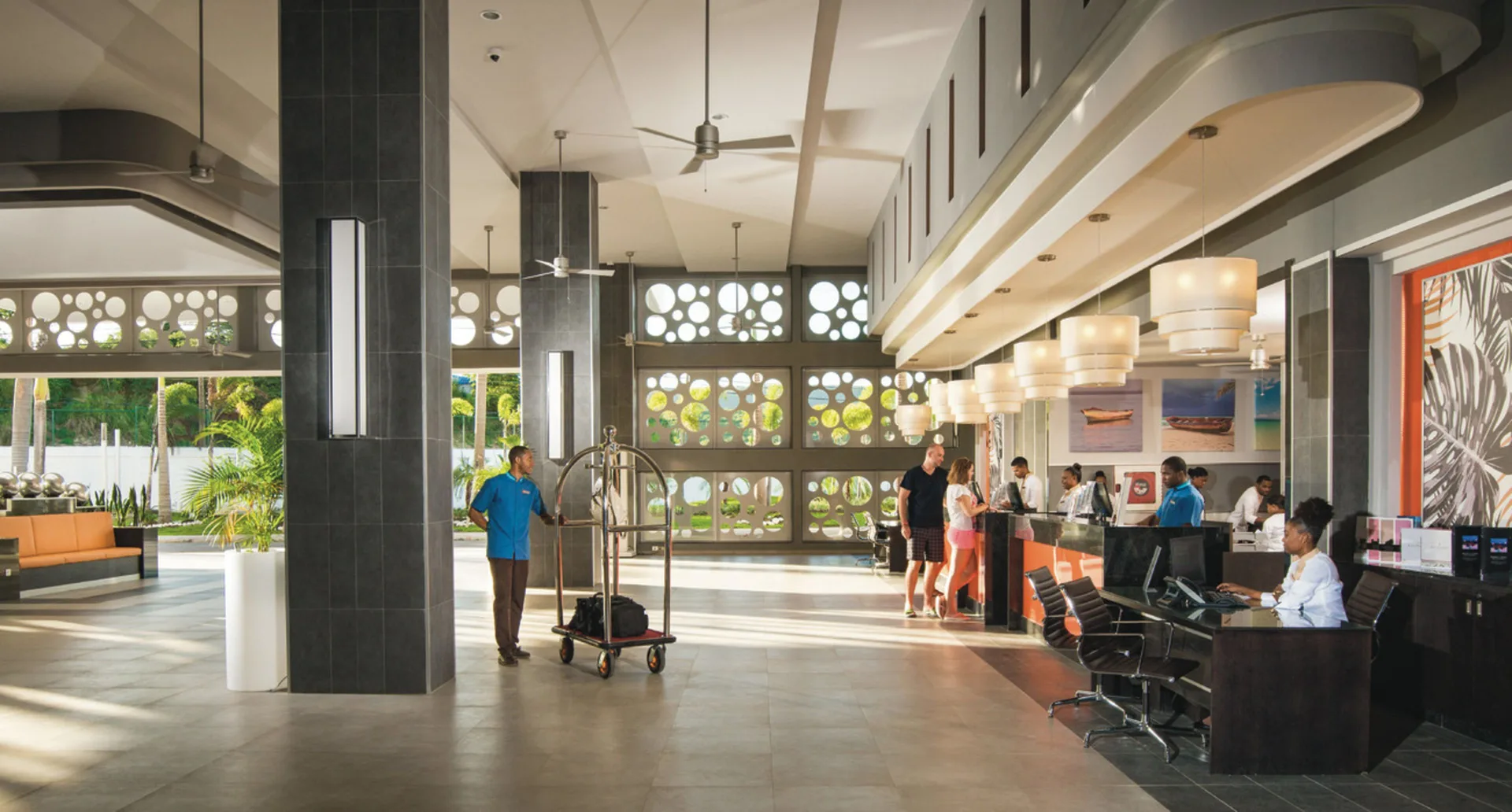 Open lobby reception area at Hotel Riu Reggae with front desk, seating, and luggage cart.
