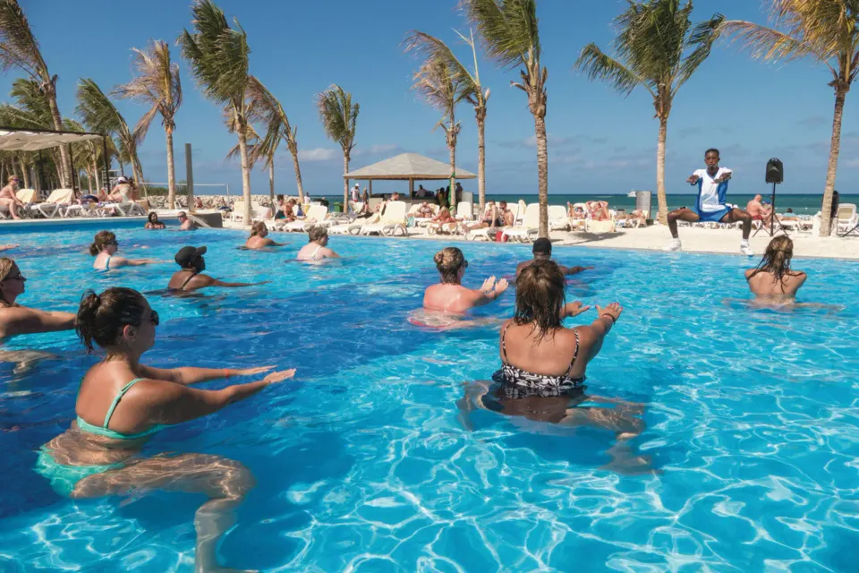 Guests join a pool fitness class beside the beach at Hotel Riu Reggae.