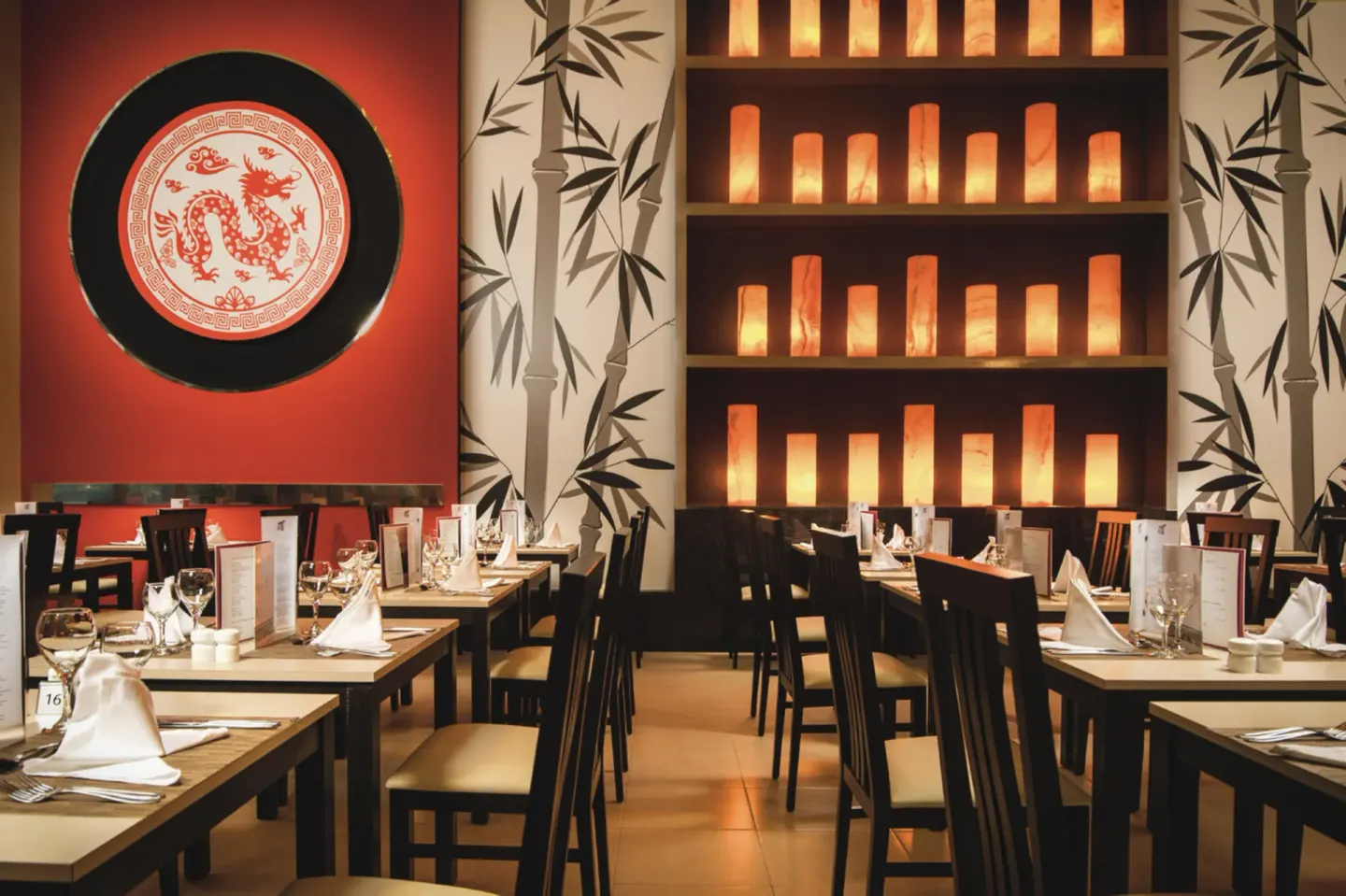 Asian-style dining room with bamboo wall art and set tables at Hotel Riu Reggae.