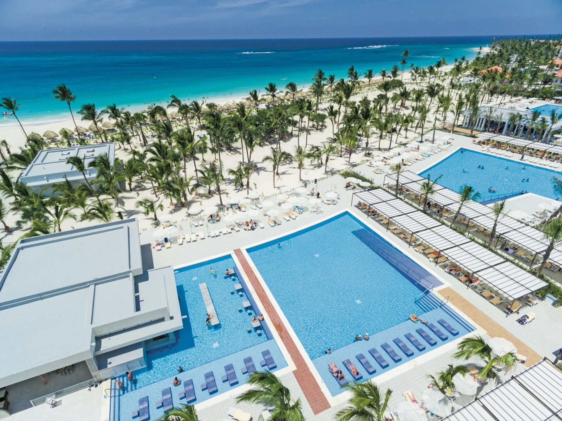 Aerial view of pools, palms, beach, and turquoise sea at Hotel Riu Republica.