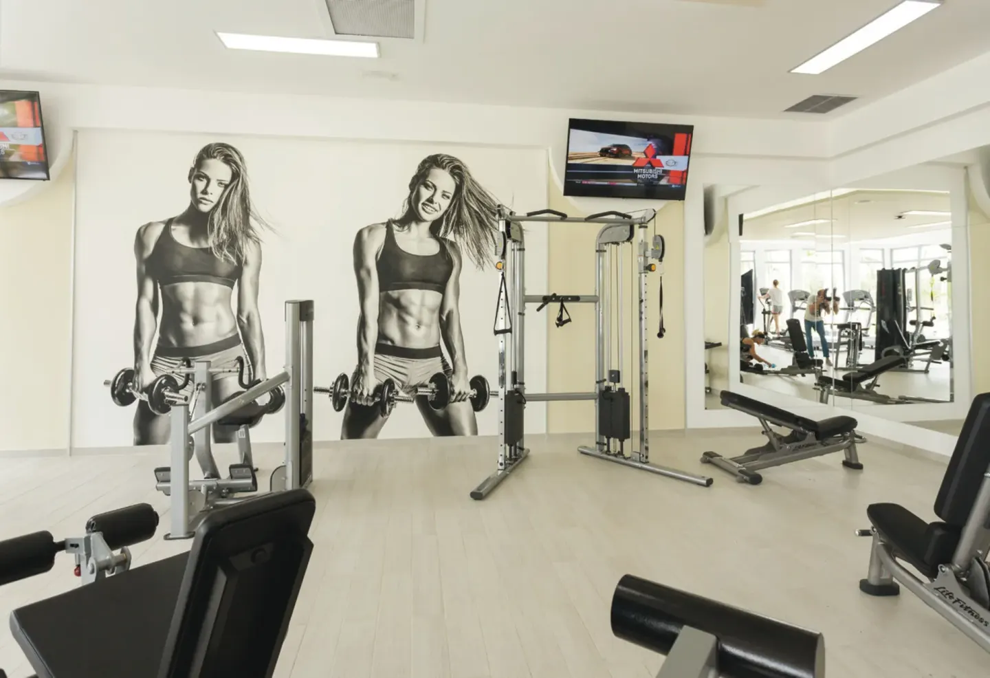 Fitness room with weight machines, benches, mirrors, and TVs at Hotel Riu Republica.