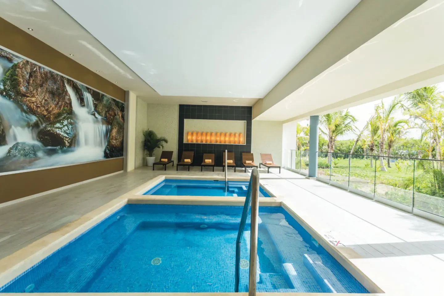 Indoor spa pools with lounge chairs and garden views at Hotel Riu Republica.