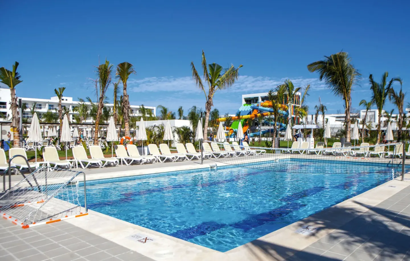Pool with volleyball nets, loungers and colorful slides at Hotel Riu Republica.