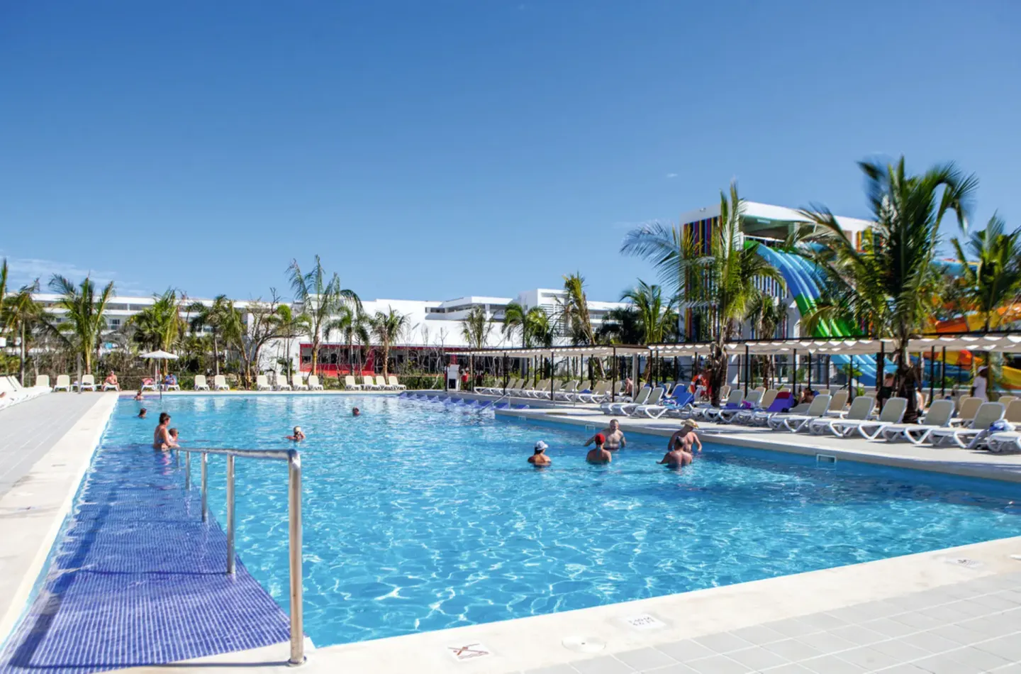 Long pool with guests, loungers and waterslides in the background at Hotel Riu Republica.