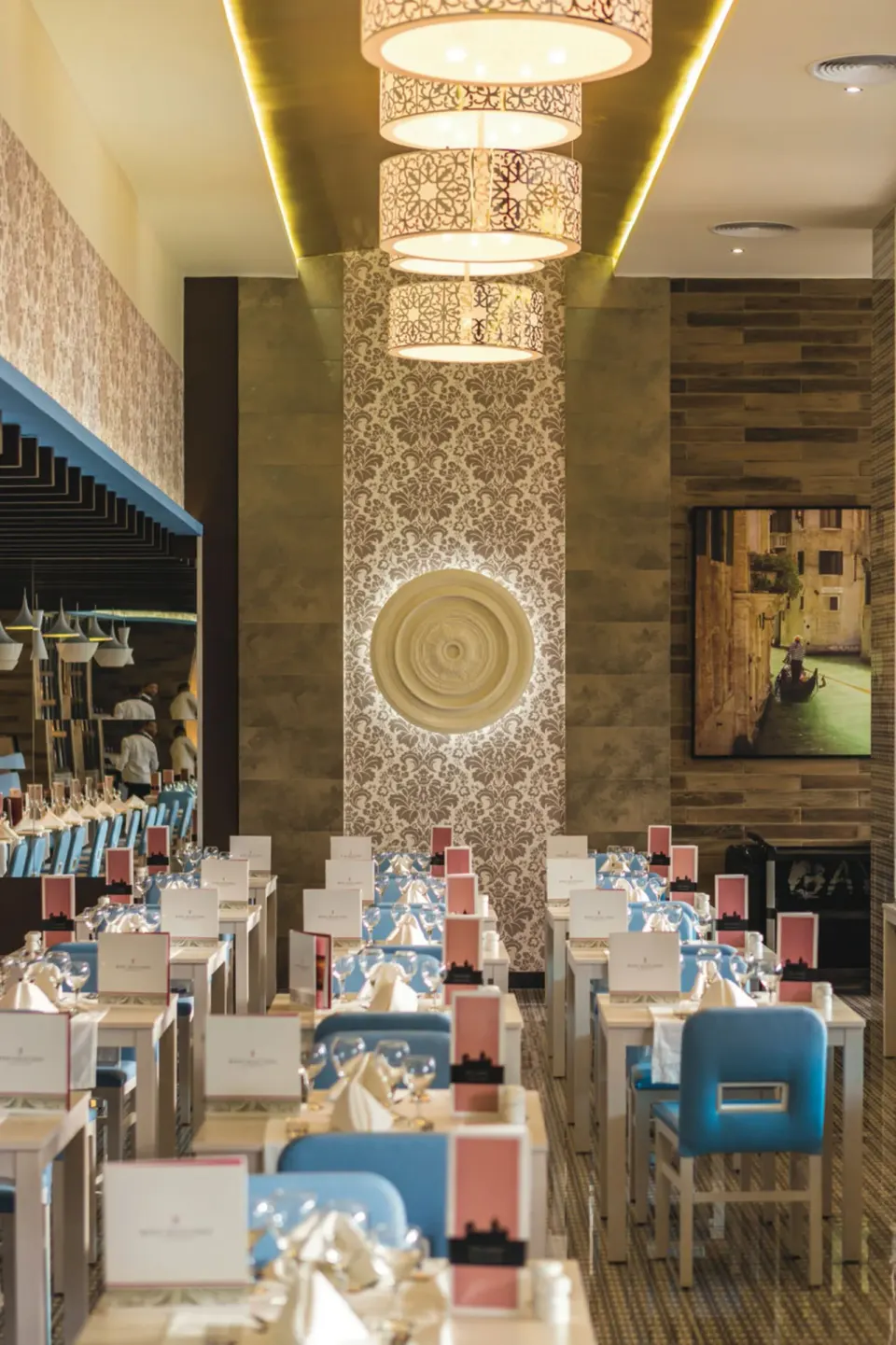 An Italian-style dining room with blue chairs and set tables at Hotel Riu Republica.