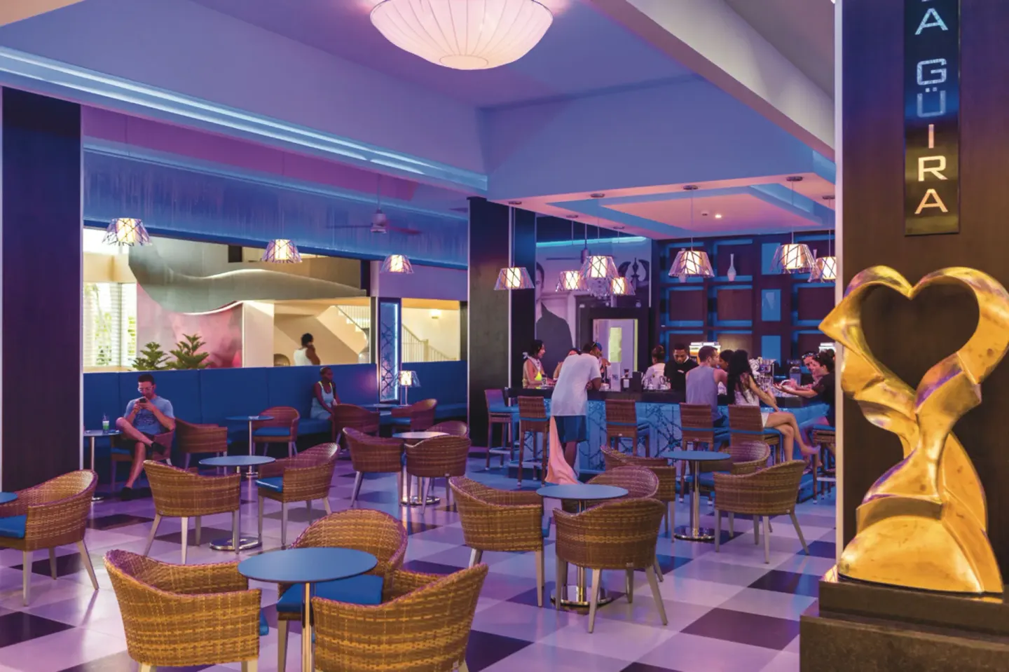 La Güira bar lounge with wicker chairs and a lit sign at Hotel Riu Republica.