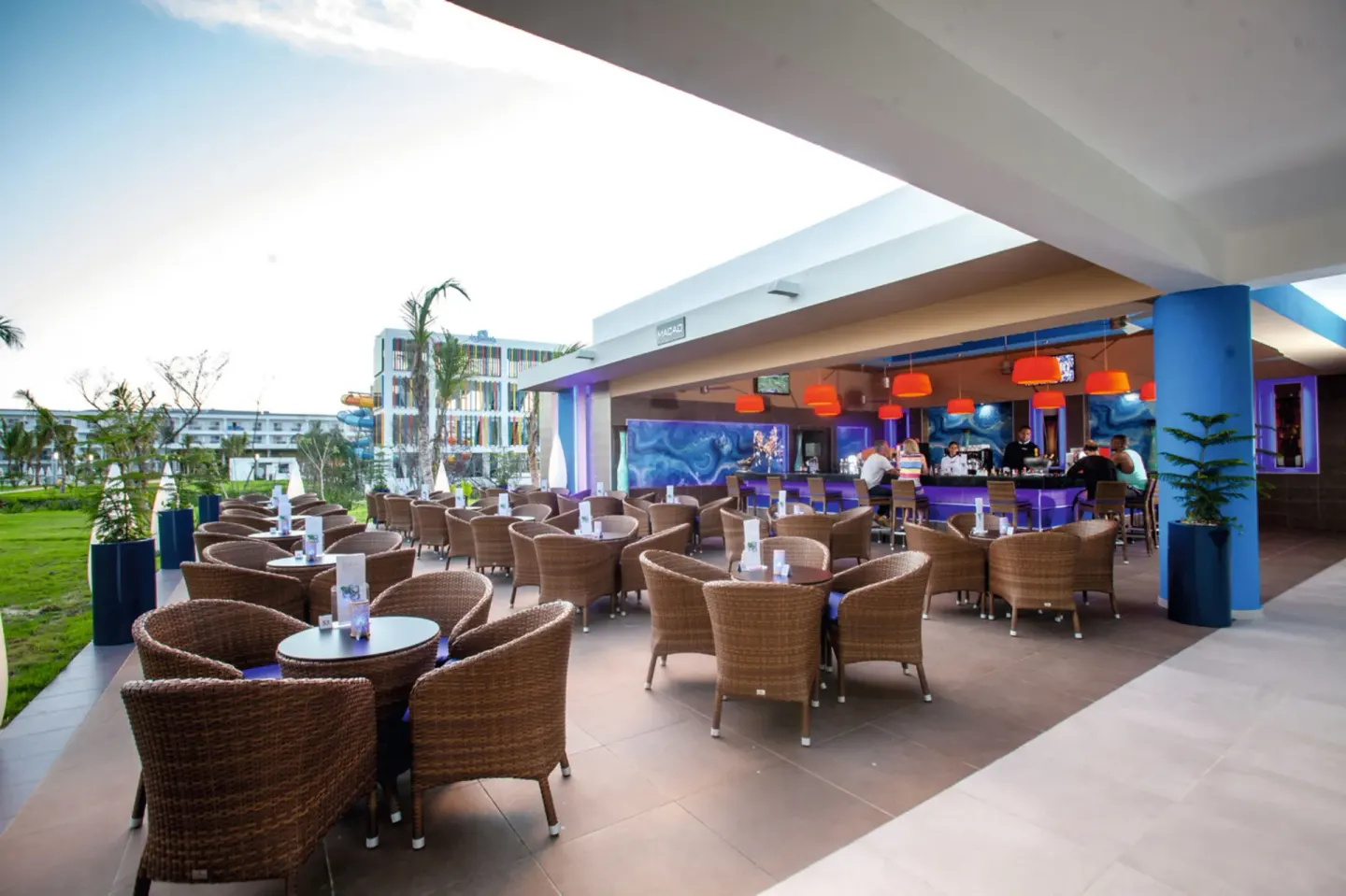 Covered Macao Bar terrace with wicker seating and orange lights at Hotel Riu Republica.