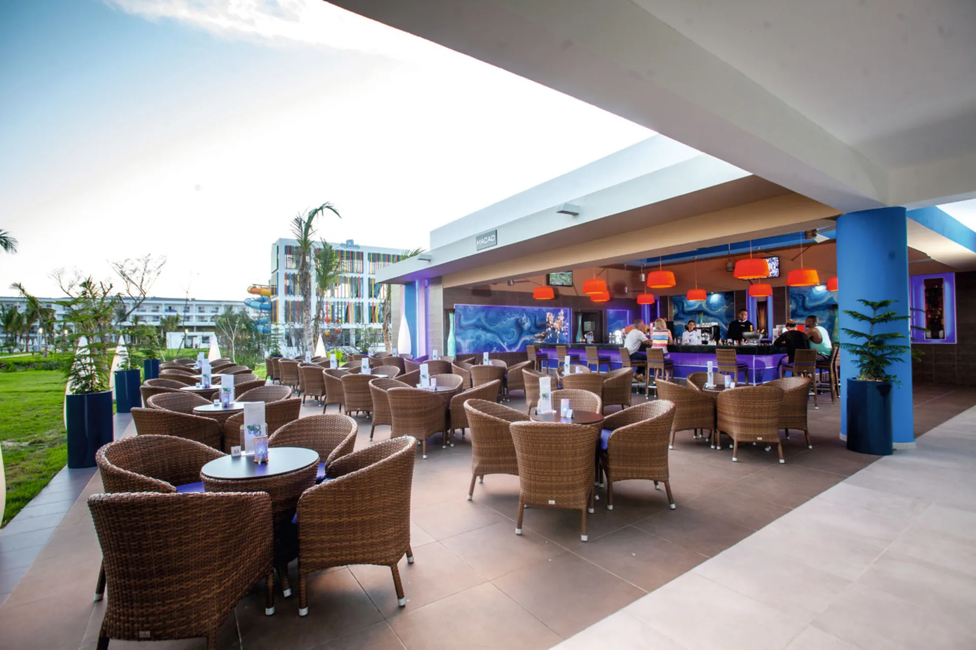 Covered Macao Bar terrace with wicker seating and orange lights at Hotel Riu Republica.