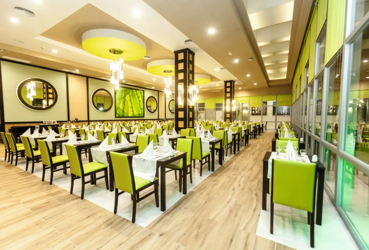 A bright restaurant dining room with lime-green chairs at Hotel Riu Republica.