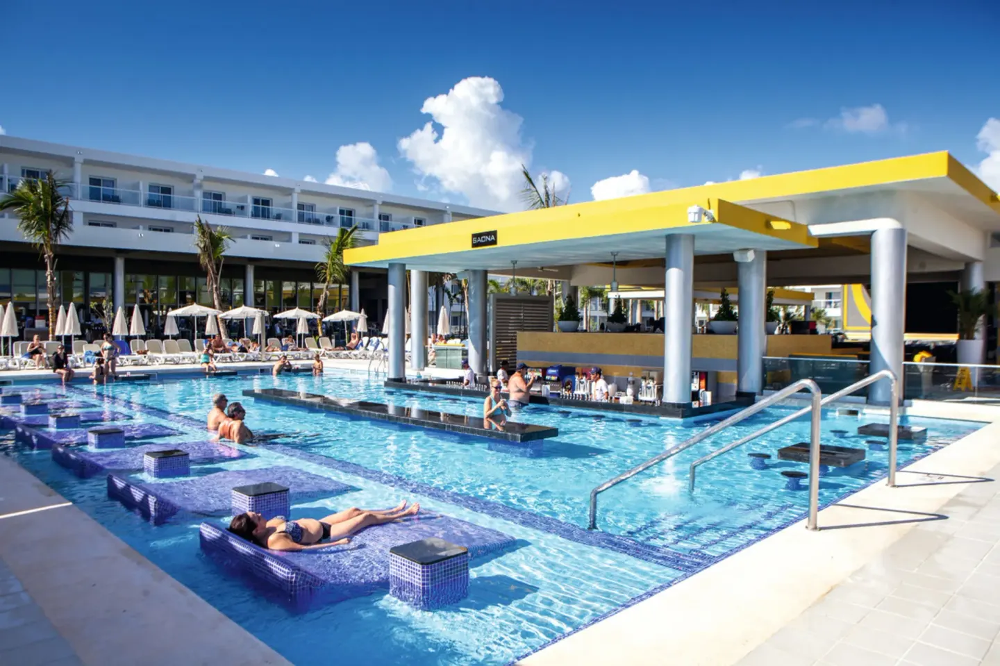 Swim-up pool bar with in-water loungers and guests at Hotel Riu Republica.