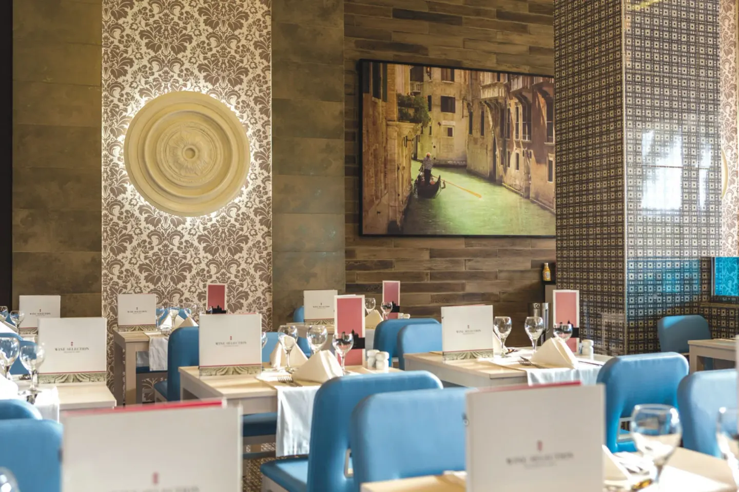Italian-style dining room with blue chairs and set tables at Hotel Riu Republica.