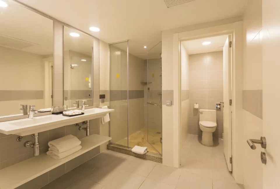 Bathroom with double sinks, glass shower, and separate toilet in the Room 2 Bedrooms at Hotel Riu Republica.