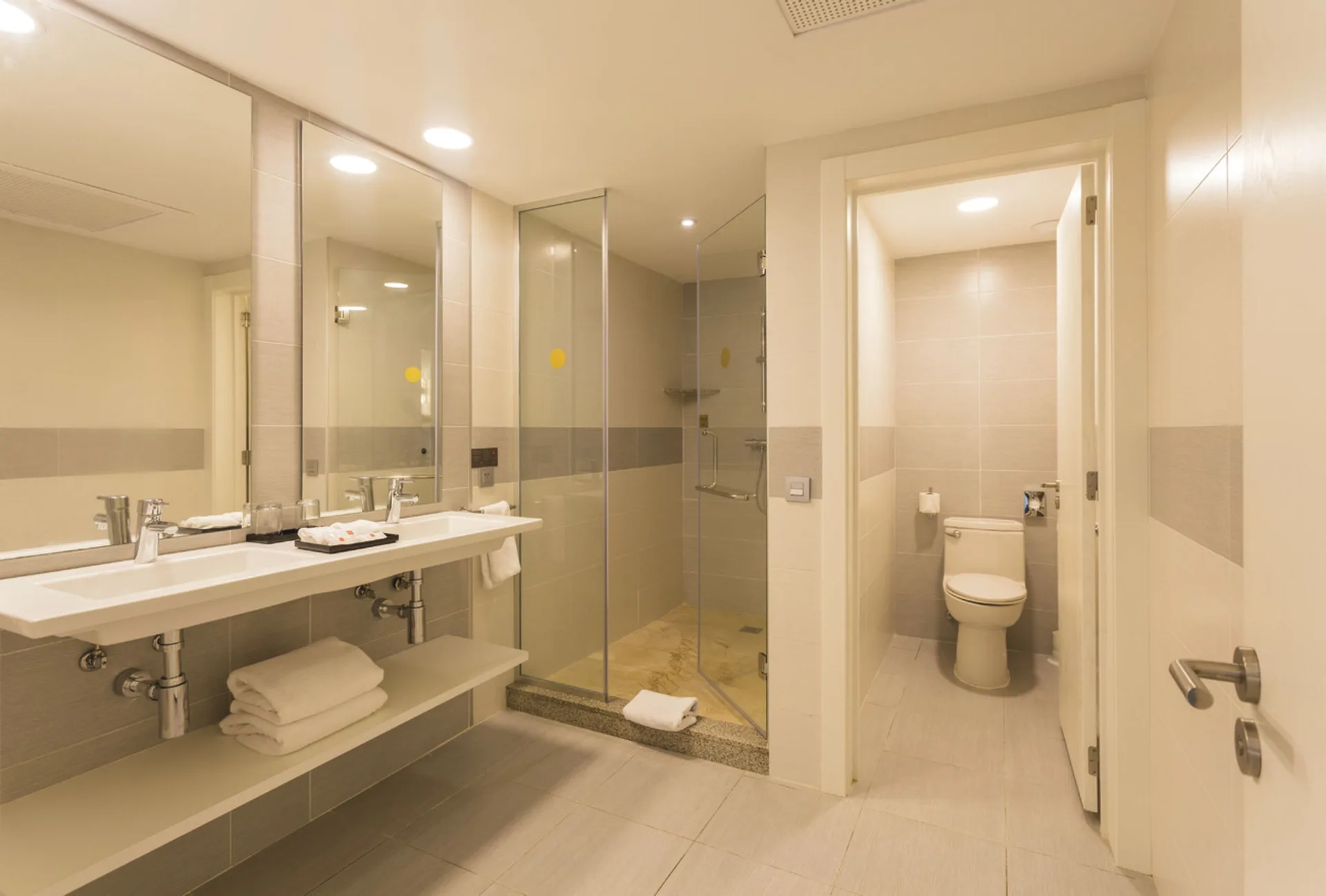 Bathroom with double sinks, glass shower, and separate toilet in the Room 2 Bedrooms at Hotel Riu Republica.