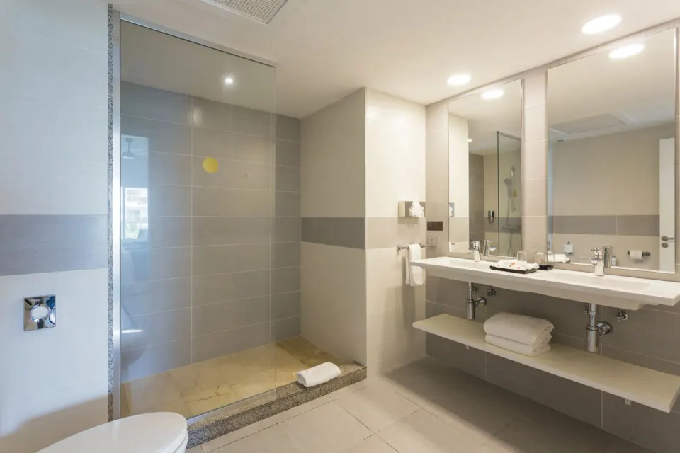 Bathroom with glass walk-in shower and long vanity in the Room 2 Bedrooms at Hotel Riu Republica.