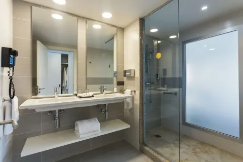 Guest room bathroom with double vanity and glass shower at Hotel Riu Republica.
