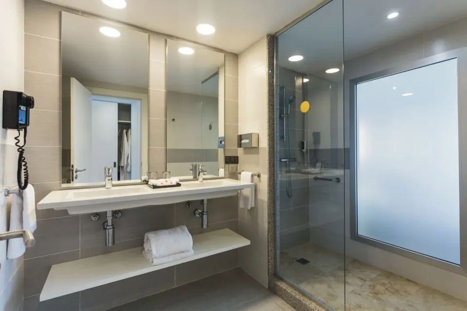 Guest room bathroom with double vanity and glass shower at Hotel Riu Republica.