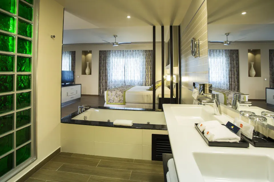 Suite bathroom with jetted tub, double sinks, mirror, and bedroom beyond at Hotel Riu Republica.