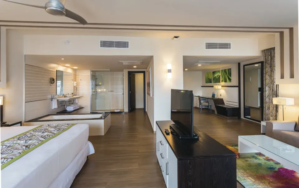 Suite with bed, open bathroom, TV, and sitting area visible at Hotel Riu Republica.