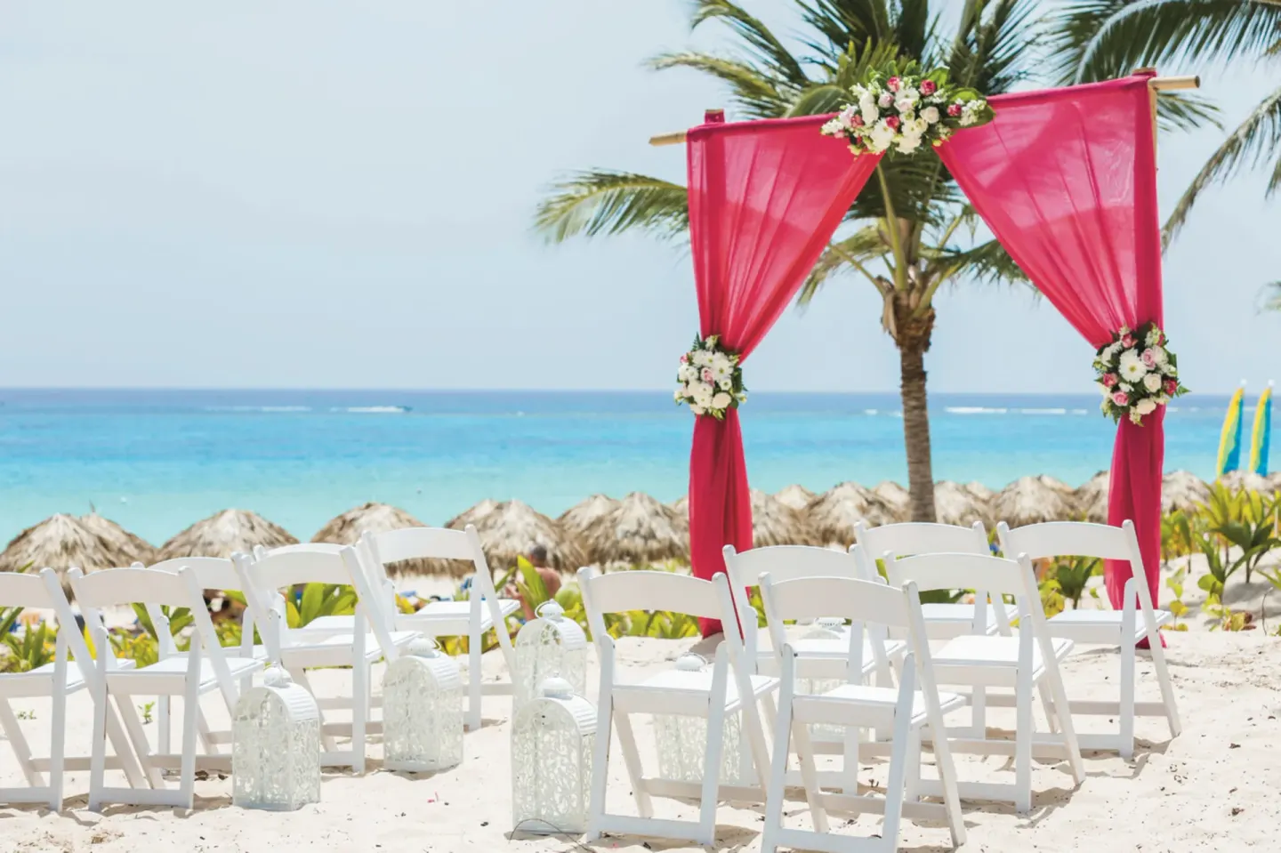 Beach wedding arch with pink draping and white chairs at Hotel Riu Republica.