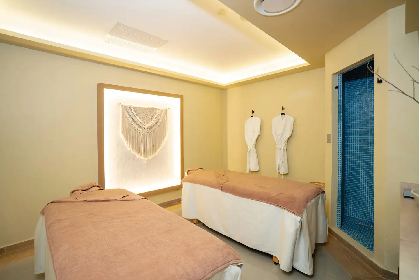 A spa treatment room with two massage beds and a blue-tiled shower at Hotel Riu Santa Fe.