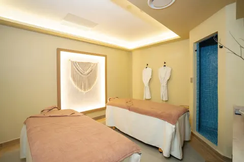 A spa treatment room with two massage beds and a blue-tiled shower at Hotel Riu Santa Fe.