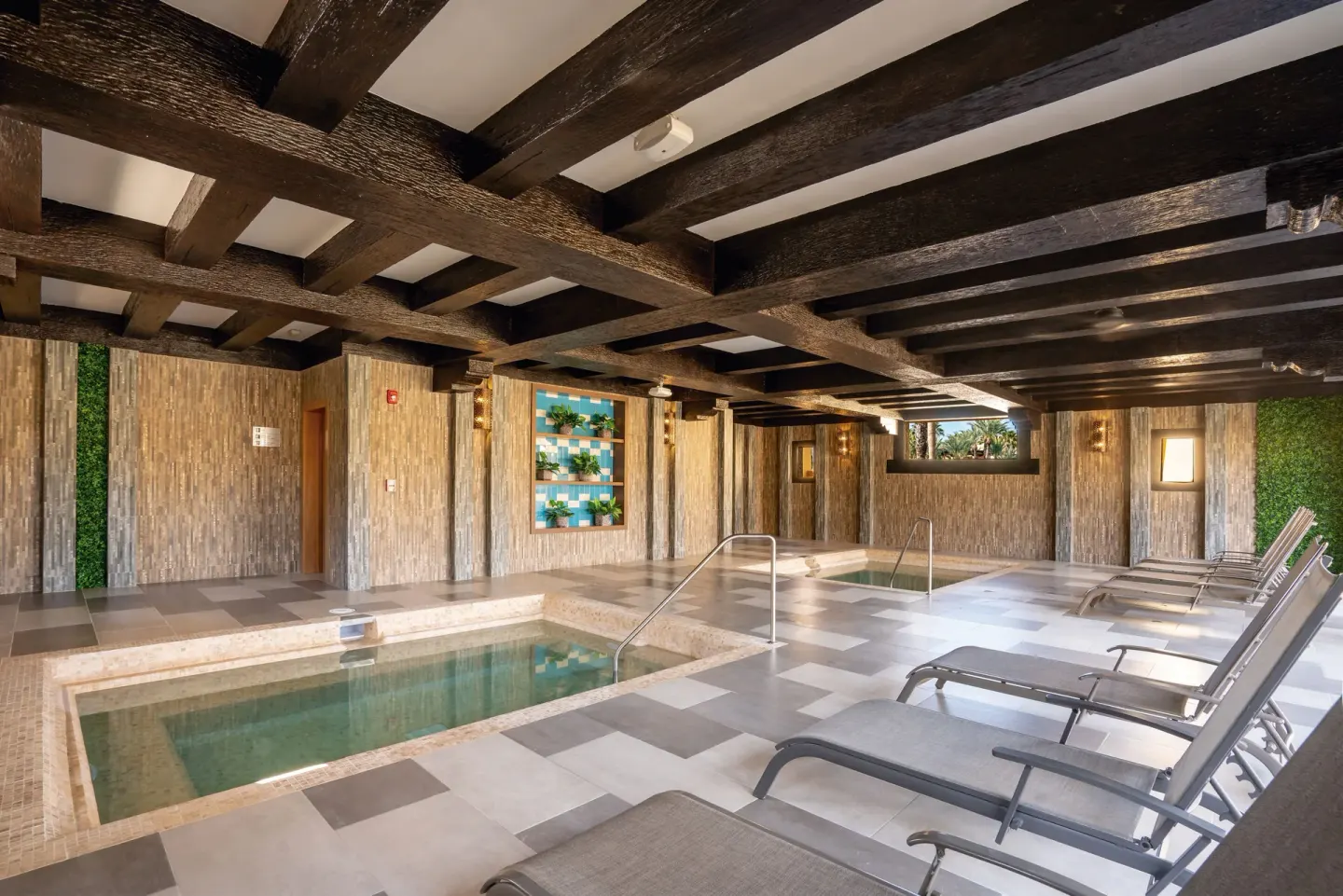 Indoor spa pools and lounge chairs sit beneath dark beams at Hotel Riu Santa Fe.