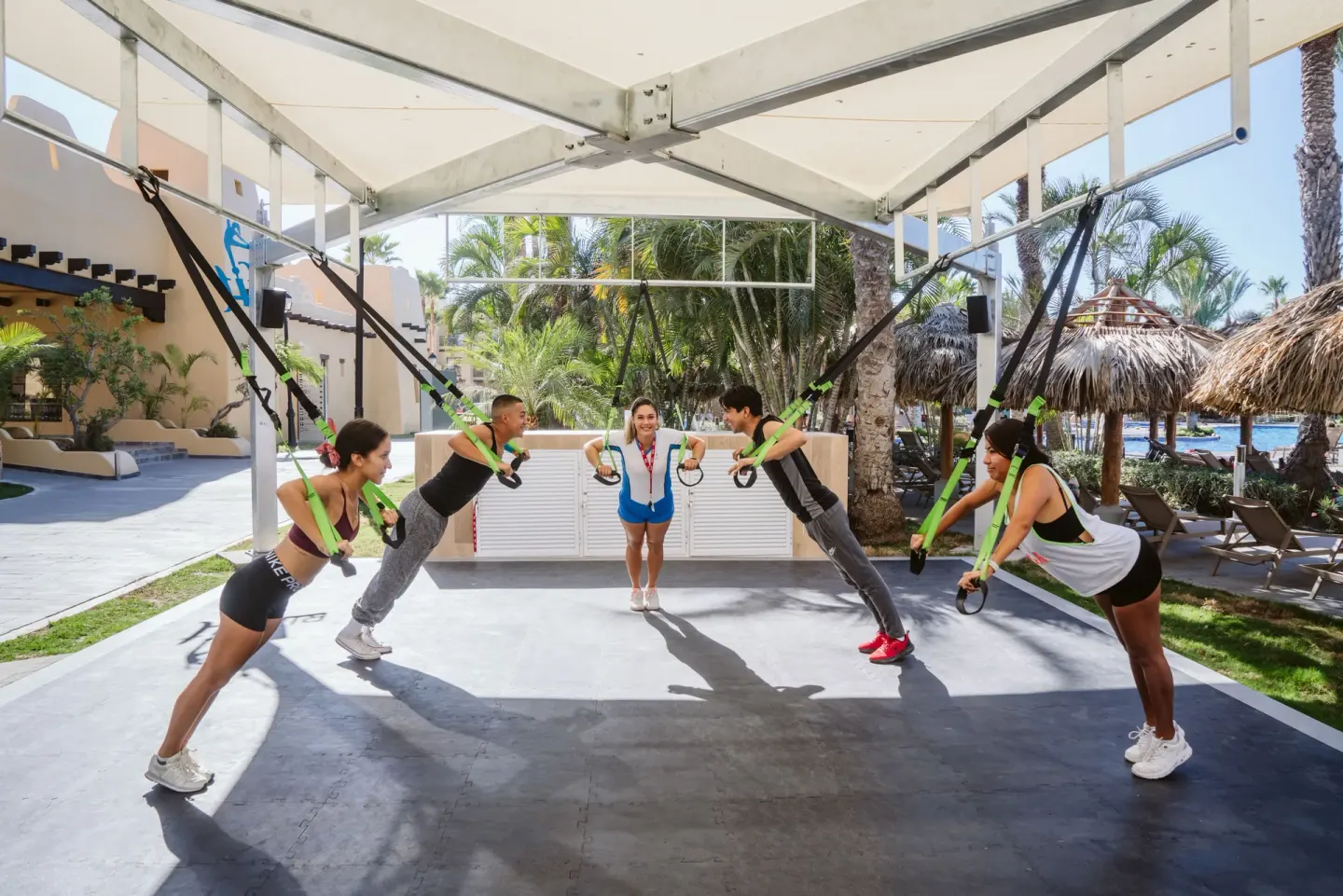 Guests use suspension straps in an outdoor fitness class at Hotel Riu Santa Fe.