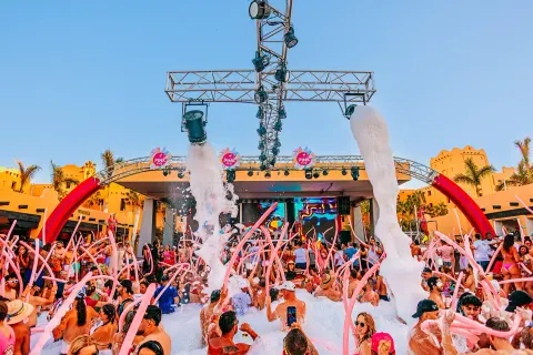 Outdoor pool foam party with pink inflatables and stage lighting at Hotel Riu Santa Fe.