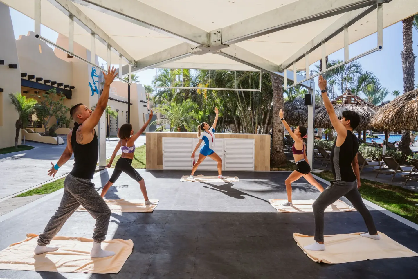 An instructor leads an outdoor yoga stretch class at Hotel Riu Santa Fe.