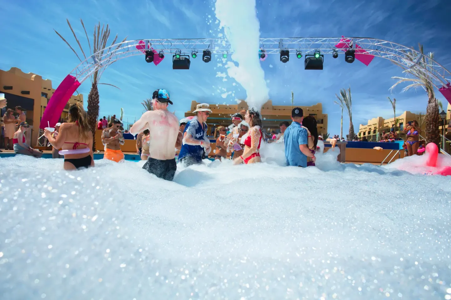 Foam party with guests dancing by the pool stage at Hotel Riu Santa Fe.