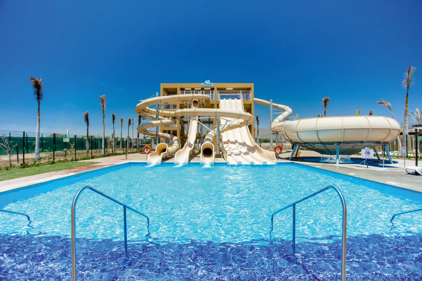 Water slides empty into a bright blue pool at Hotel Riu Santa Fe.