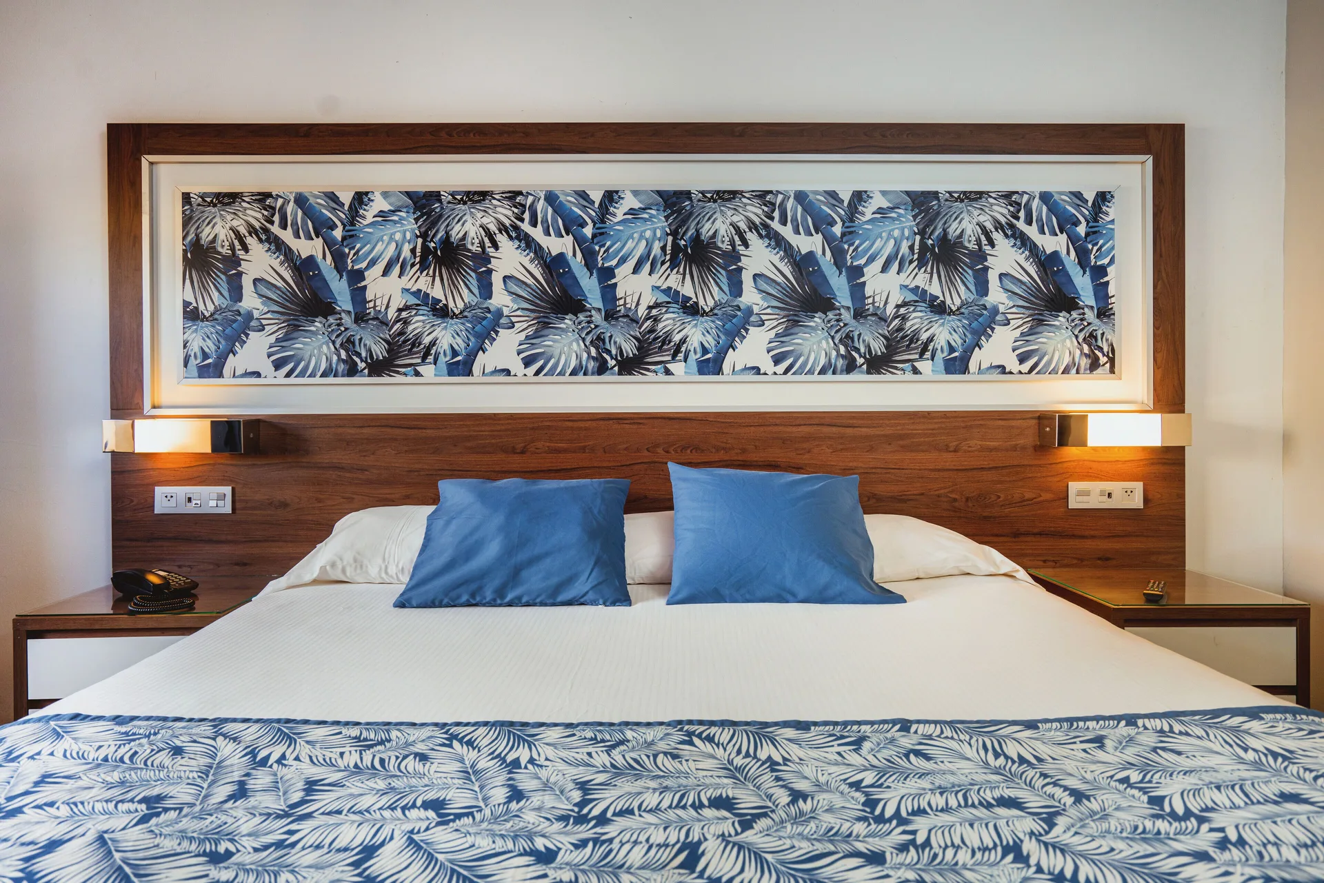 Hotel Riu Santa Fe bed at Hotel Riu Santa Fe with blue pillows and tropical wall art.