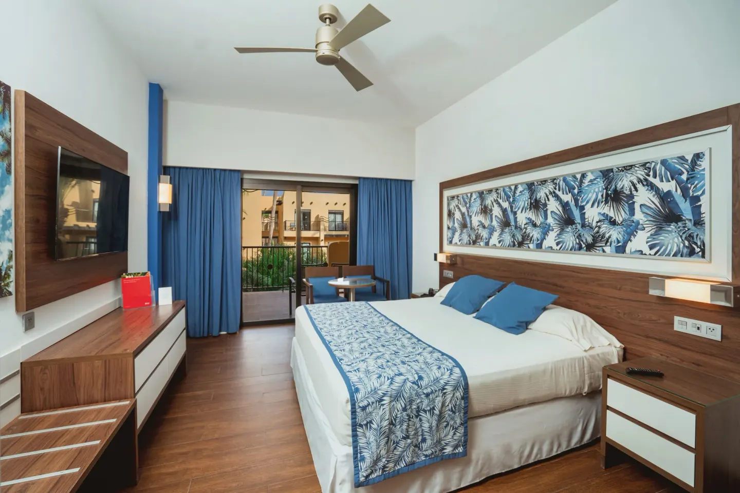 Hotel Riu Santa Fe at Hotel Riu Santa Fe with king bed, wall-mounted TV and balcony doors.