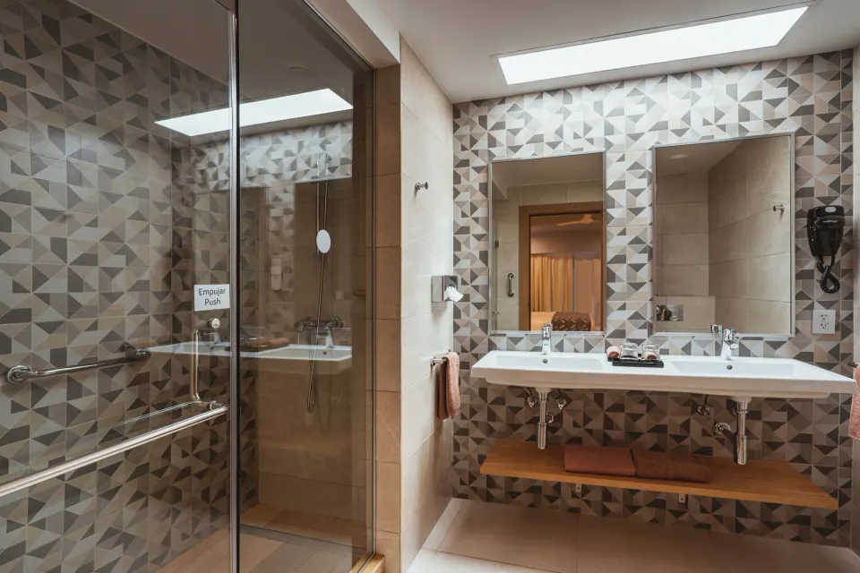 Guest room bathroom with double sinks and glass shower at Hotel Riu Santa Fe.