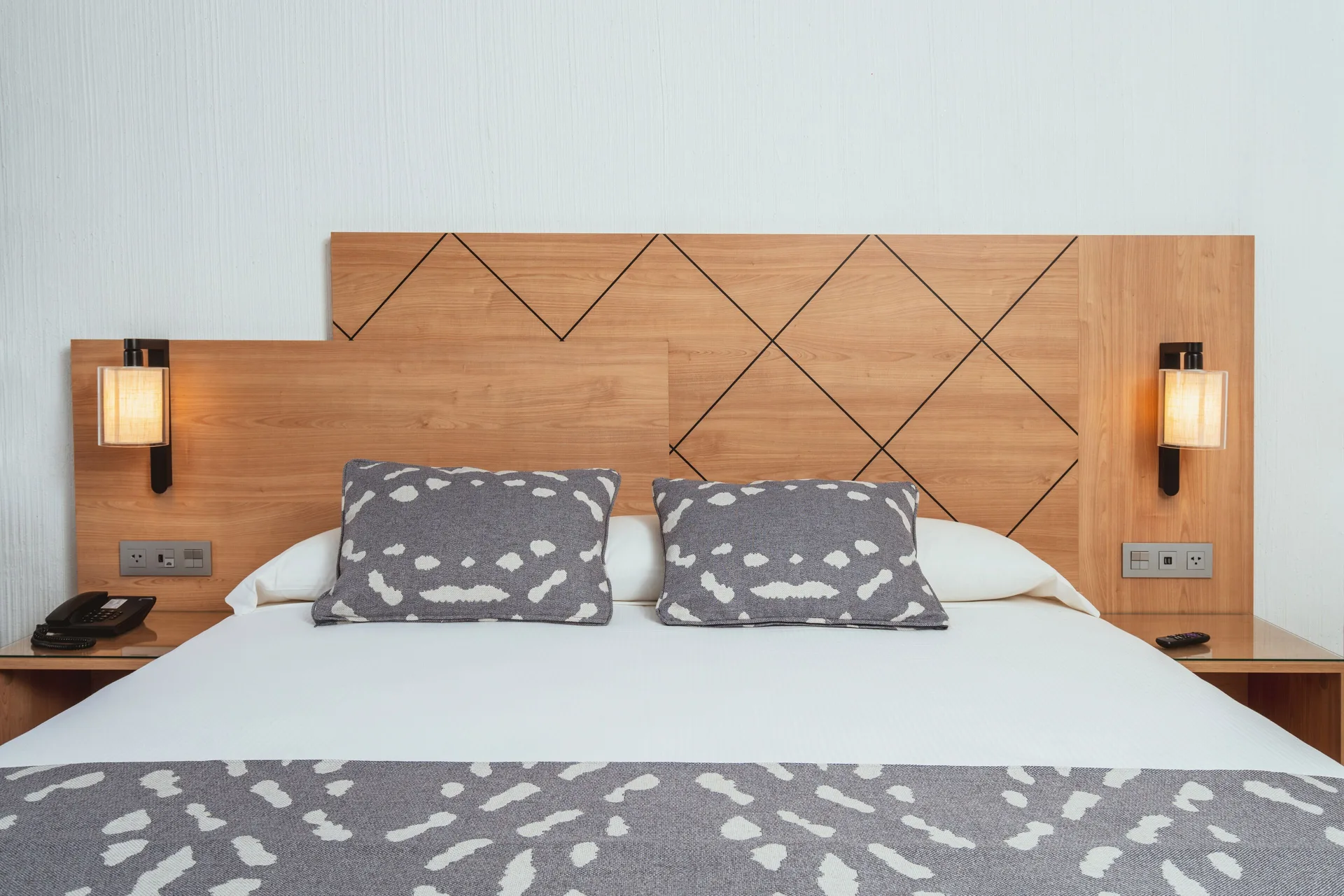 King bed with patterned pillows and wood headboard at Hotel Riu Santa Fe.
